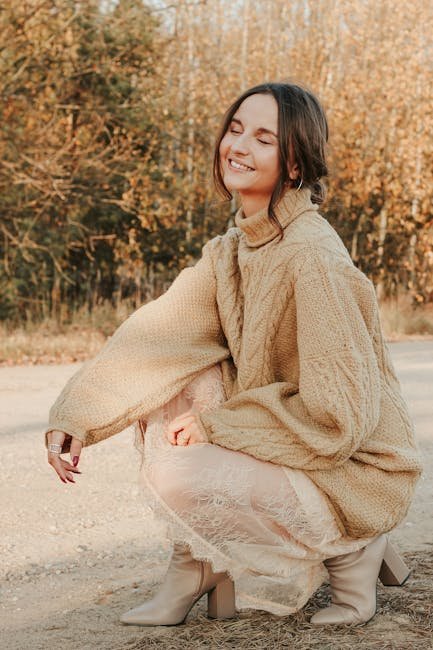 Young woman smiling outdoors in Minsk wearing a cozy beige sweater.